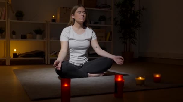 Młoda kobieta medytująca w domu, siedząca na podłodze. Nastolatek oddycha głęboko w pozycji lotosu. - Materiał filmowy, wideo