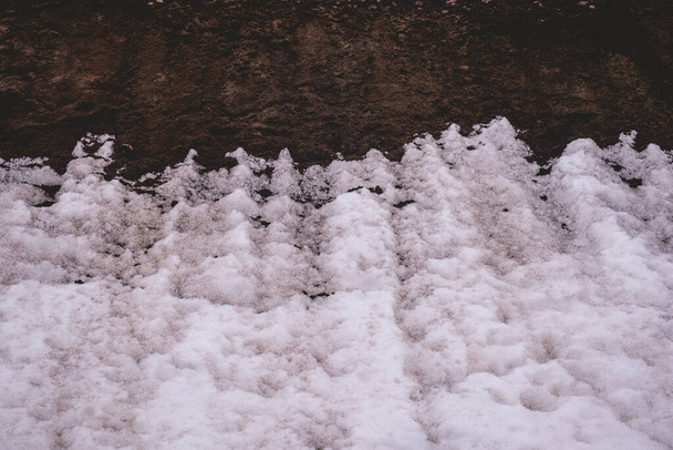 Çelişkili elementler: Koyu toprak ve beyaz kar arasındaki sert sınıra yakın çekim "dalgası" - Fotoğraf, Görsel