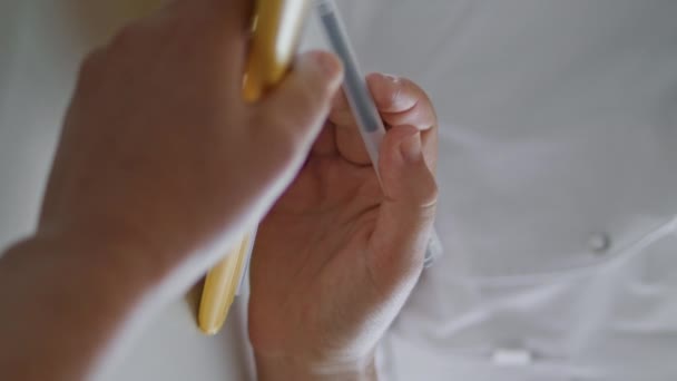Vrouw handen met pen tonen details in documenten aan cosmetoloog dragen badjas verticaal georiënteerde close-up. Onbekende vrouwelijke cliënt leest papieren overeenkomst over chirurgie met medisch specialist zitkantoor - Video
