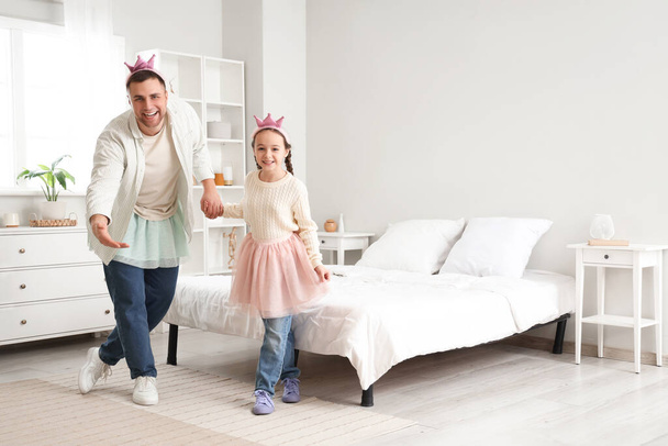 Батько і його дочка в костюмах принцеси грають у спальні - Фото, зображення