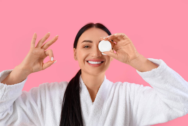 Linda jovem mulher feliz em roupão de banho com fio dental mostrando gesto OK em fundo rosa - Foto, Imagem