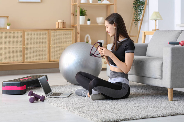 Blogger deportiva con expansor de fitness y portátil en casa - Foto, imagen