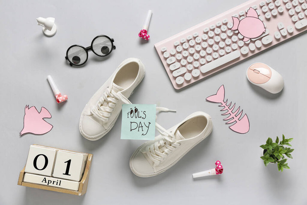 Zapatos con cordones atados, teclado de ordenador y calendario sobre fondo blanco. Broma del Día de los Inocentes - Foto, Imagen