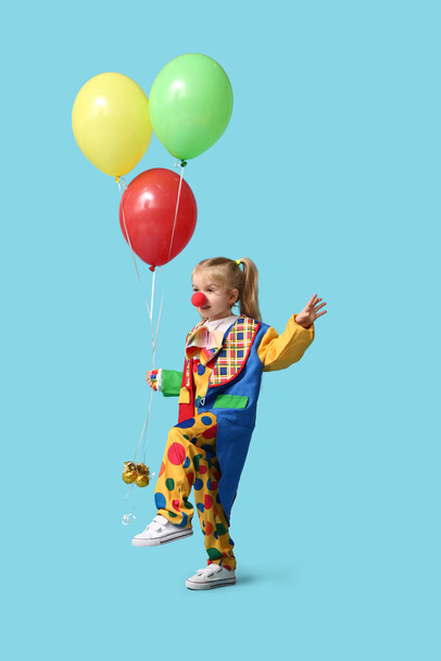 Aranyos kislány bohóc jelmezben lufikkal a kék háttéren - Fotó, kép