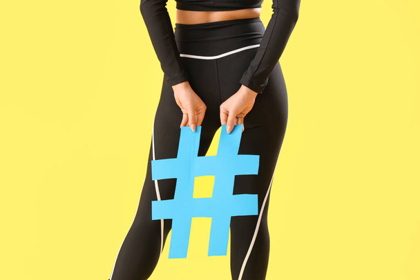 Bella ragazza griglia in possesso di hashtag segno su sfondo giallo, vista posteriore - Foto, immagini