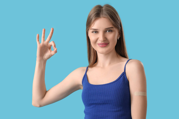 Mulher muito jovem com patch médico aplicado mostrando gesto OK em fundo de cor - Foto, Imagem