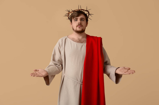 Homme en Jésus robe et couronne d'épines avec les mains étendues sur fond beige - Photo, image