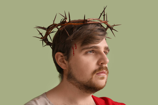 Homme en Jésus robe et couronne d'épines avec du sang sur fond vert - Photo, image