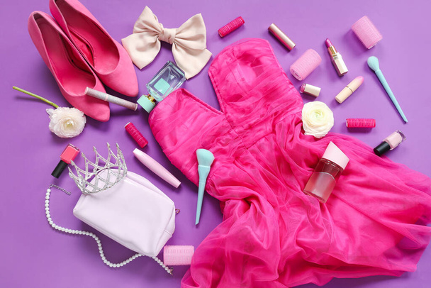 Vrouwelijke prom outfit met make-up producten, accessoires en bloemen op paarse achtergrond - Foto, afbeelding