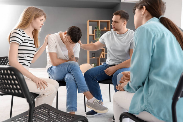 Jóvenes calmando a hombre triste en sesión de terapia de grupo - Foto, Imagen