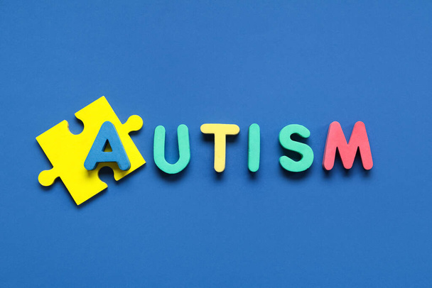 AUTISMO palavra e quebra-cabeça em fundo azul. Conceito de transtorno autista - Foto, Imagem