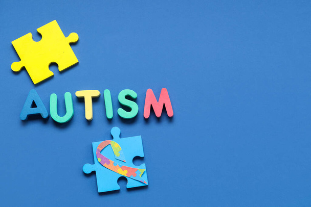 Word AUTISM en puzzel op blauwe achtergrond. Begrip autistische stoornis - Foto, afbeelding