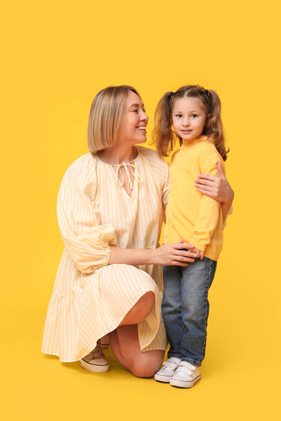 Ευτυχισμένη οικογενειακή μητέρα και το παιδί της μαζί σε κίτρινο φόντο. Ημέρα της Μητέρας - Φωτογραφία, εικόνα