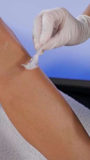 化粧品学者はレーザーの毛の取り外しの前に患者の足に冷却ゲルを加えます - 映像、動画