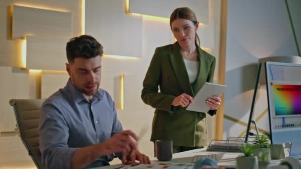 Ciddi bir yönetici elinde tablet bulunan kendine güvenen kadın CEO 'ya iş sonuçlarını gösteriyor. Yaratıcı iş yerinde proje sorunlarını tartışan iki profesyonel tasarımcı. Masadaki örneklere bakan tasarım uzmanları.. - Video, Çekim