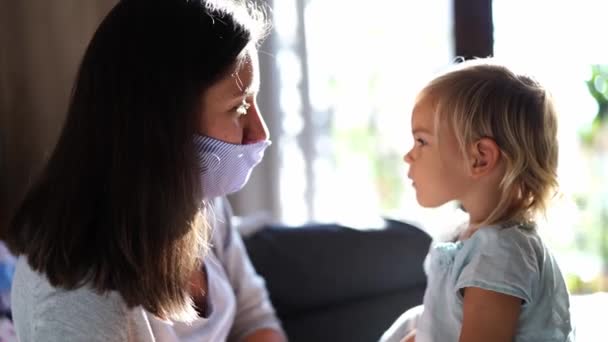 Little girl takes off the protective mask from her mother face and kisses her. High quality 4k footage - Footage, Video