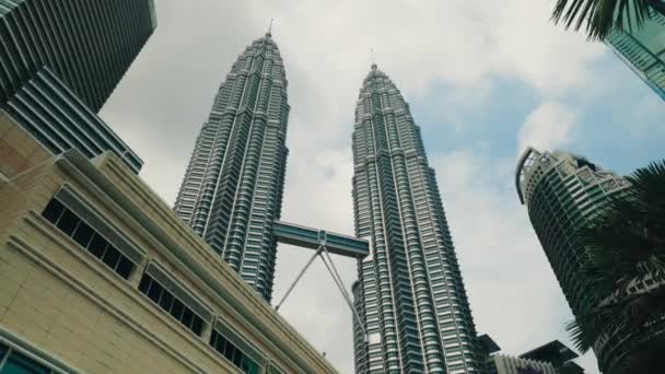 KUALA LUMPUR, MALAYSIA - 3. Januar 2024: Petronas Zwillingstürme aus dem Boden zwischen den Gebäuden. Niedriger Blick auf futuristische Türme in der Innenstadt. Kuala Lumpur. Tourismus- und Reisekonzept - Filmmaterial, Video