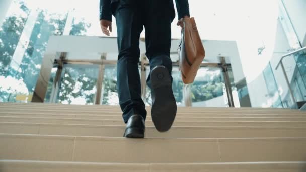 Zbliżenie nogi biznesmena wchodzi po schodach. Udany człowiek wchodzący po schodach i odkrywający nowe rzeczy. Podróże, awans, znalezienie nowej pracy, podnoszenie umiejętności. Widok z tyłu. Ekstrakt. - Materiał filmowy, wideo