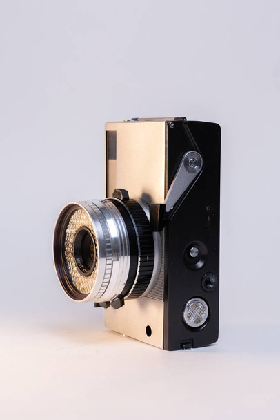 Pürüzsüz gümüş bir vücudu ve klasik siyah manuel odaklı objektifi olan klasik bir film kamerası, beyaz arka planda zarif bir şekilde gösteriliyor.. - Fotoğraf, Görsel
