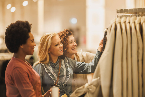 Aufnahme von drei Freundinnen beim Anblick von Kleidung in Boutique. - Foto, Bild