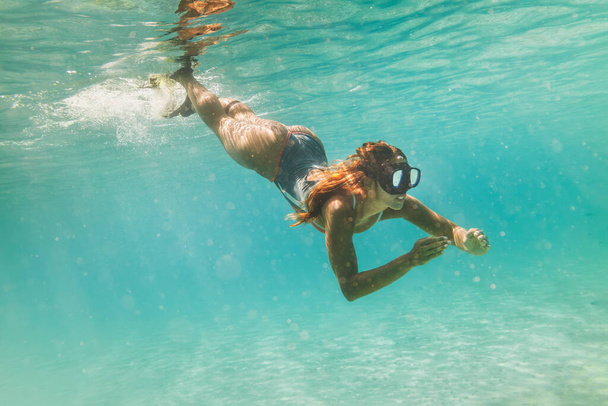 Una hermosa joven se divierte en las vacaciones de verano explorando el fondo del mar durante el buceo en el mar
. - Foto, Imagen