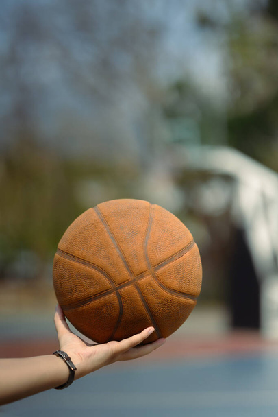 Großaufnahme eines Basketballspielers, der einen Ball auf einem Außenplatz hält. Menschen, Sport und aktiver Lebensstil. - Foto, Bild
