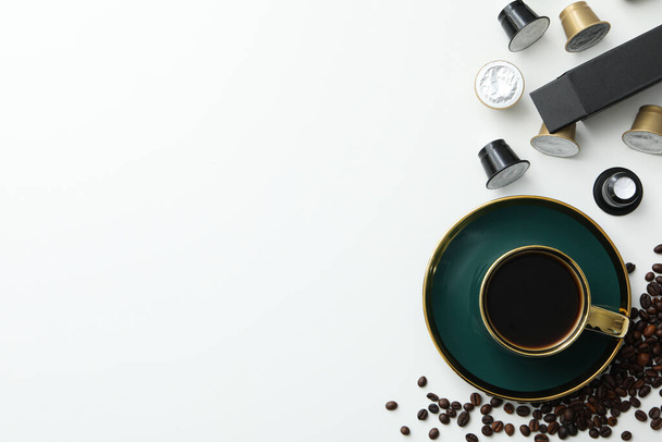 Κάψουλες καφέ και φασόλια, κύπελλο με καφέ ποτό σε λευκό φόντο, χώρος για κείμενο - Φωτογραφία, εικόνα