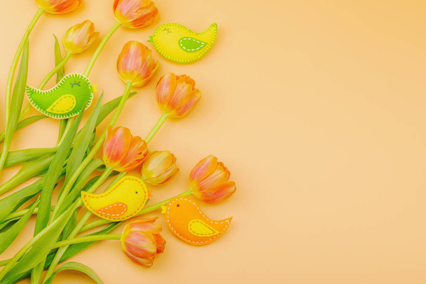 Hellävarainen pääsiäinen koostumus tulppaanit kukkia ja käsintehtyjä huopa lintuja. Perinteiset koriste-elementit, onnittelukortti. Tasainen lay, aprikoosi tausta, ylhäältä - Valokuva, kuva