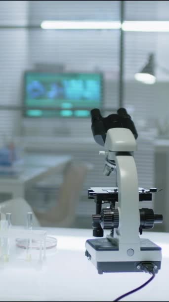 Vertical ninguna persona disparo de microscopio en mesa blanca en laboratorio científico moderno - Imágenes, Vídeo