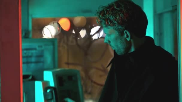 Ein Mann steht in einer Telefonzelle. Er blickt mit ernster Miene auf den Bildschirm - Filmmaterial, Video