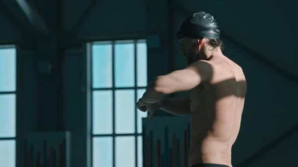 Střední sklon dolů boční záběr mladého sportovce dělat otáčení pasu cvičení, pak se ohýbat, držet se potápěčského bloku a protahování jádra svalů, zatímco se připravuje na trénink v bazénu - Záběry, video