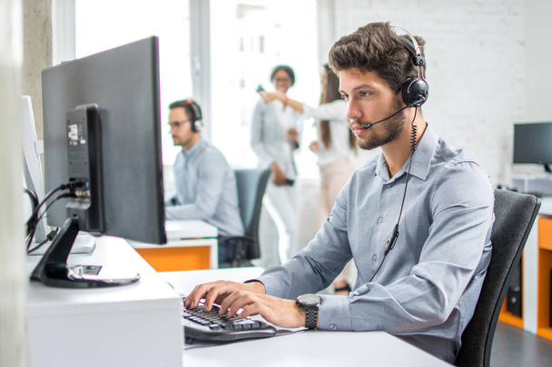 Fiatal jóképű férfi ügyfélszolgálat telefon operátor headset dolgozik call center - Fotó, kép