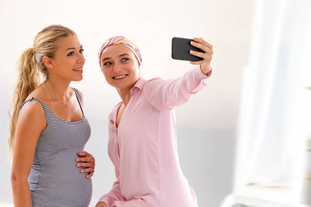 Dos mujeres jóvenes en el hospital tomando una selfie durante una visita - Foto, Imagen