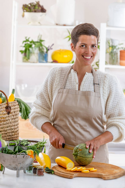 Молодая женщина с кухонным фартуком в окружении органических овощей - Фото, изображение