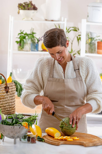 Молодая женщина с кухонным фартуком в окружении органических овощей - Фото, изображение