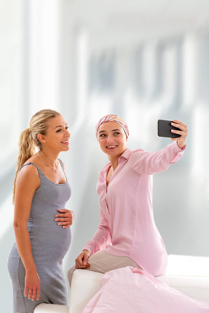Kaksi nuorta naista sairaalassa ottamassa selfietä vierailun aikana - Valokuva, kuva