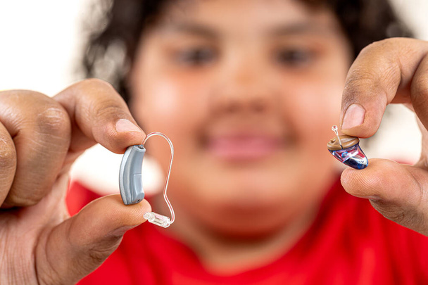 Menino de 14 anos escolhendo entre dois aparelhos auditivos diferentes. - Foto, Imagem
