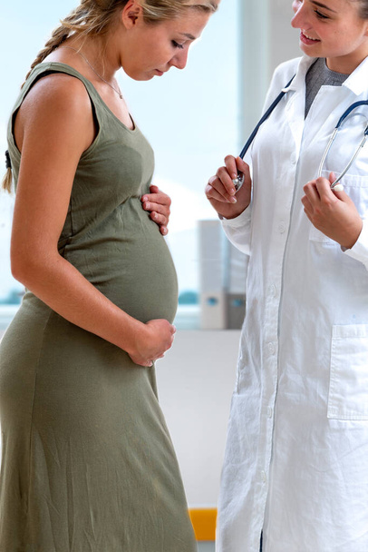 Γιατρός στέκεται μπροστά από 7 μηνών έγκυος ασθενή του. - Φωτογραφία, εικόνα