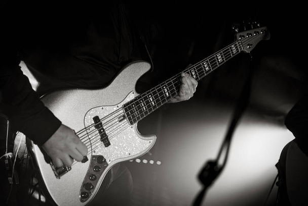 Close-up de uma guitarra baixo durante uma apresentação de concerto. Preto e branco Guitarrista baixo no palco - Foto, Imagem