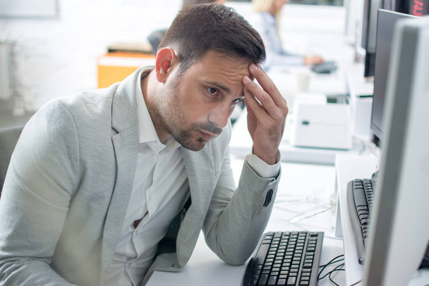Бізнесмен має головний біль під час роботи на комп'ютері в офісі - Фото, зображення