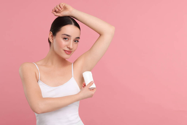 Beautiful woman applying deodorant on pink background, space for text - Foto, imagen
