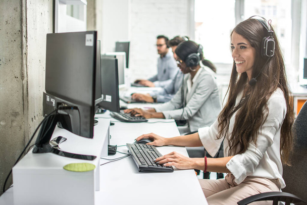 Joven empresaria sonriente trabajando con colegas en una oficina de call center, operadores de soporte técnico - Foto, imagen