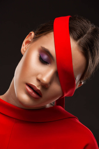 Portrait of a beautiful young woman with bright makeup in a red dress. - Foto, afbeelding