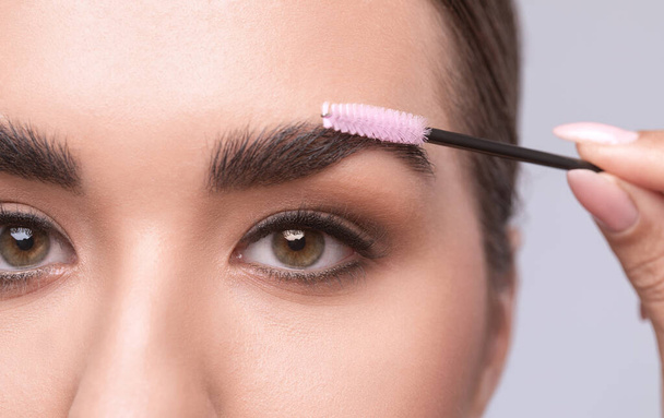 Visagistin kämmt und zupft Augenbrauen in einem Schönheitssalon. Professionelles Make-up und kosmetische Hautpflege. - Foto, Bild