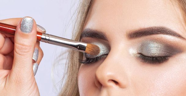 Schöne Augen einer Frau mit leuchtendem Make-up in Nahaufnahme. Make-up und gesunde, saubere Haut. Professionelles Make-up-Konzept - Foto, Bild