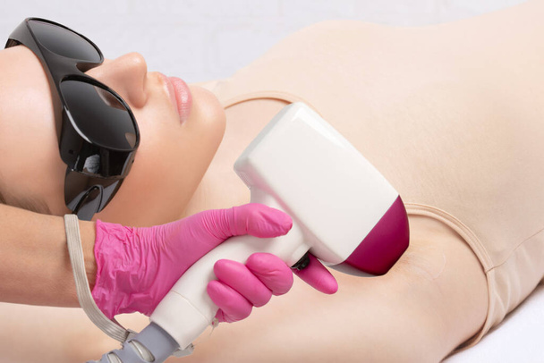 epilation hair removal procedure on a womans body. Beautician doing laser rejuvenation in a beauty salon. Removing unwanted body hair. Hardware ipl cosmetology - Photo, Image