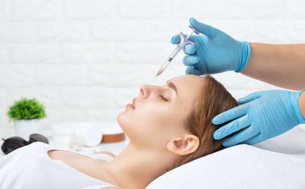 The doctor does injections to correct the hump on the nose. The beautician doeses injections against wrinkles on the face. Women's cosmetology in a beauty salon. - Photo, Image
