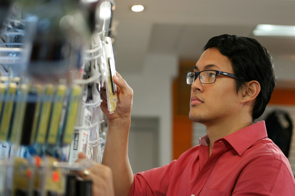Chiński człowiek zamawiania dysku Usb na półce w sklepie komputer - Zdjęcie, obraz