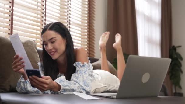 インターネットバンキング用のクレジットカード付きのラップトップを使用してソファに横たわる若い女性,自宅でオンライン決済ゲートウェイでオンラインショッピングEコマース. モダンで便利なオンライン購入. ブリテット - 映像、動画