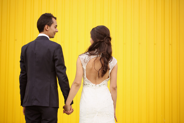 Bride and Groom facing yellow wall - Фото, изображение